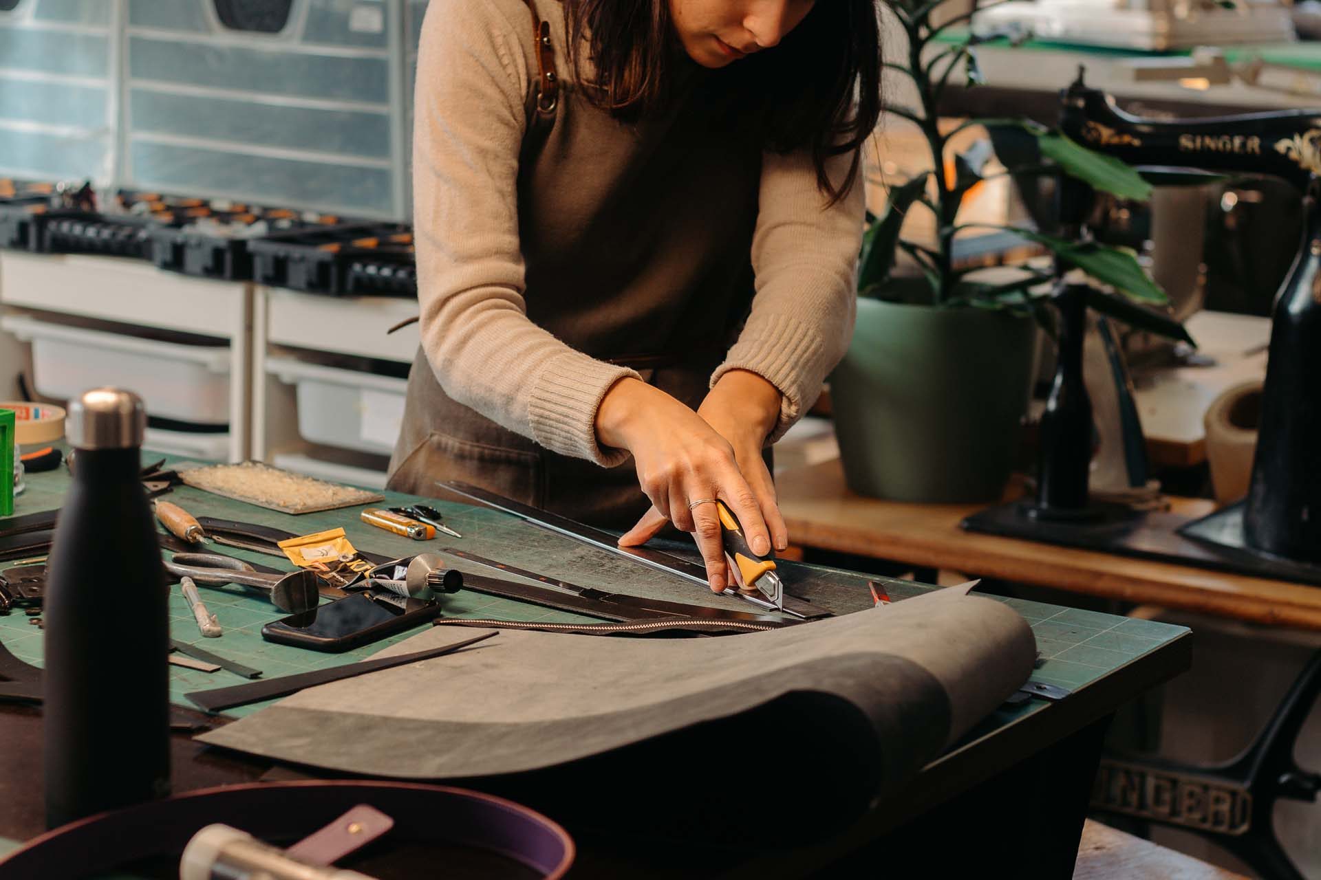 A crafter cutting leather with a knife and ruler