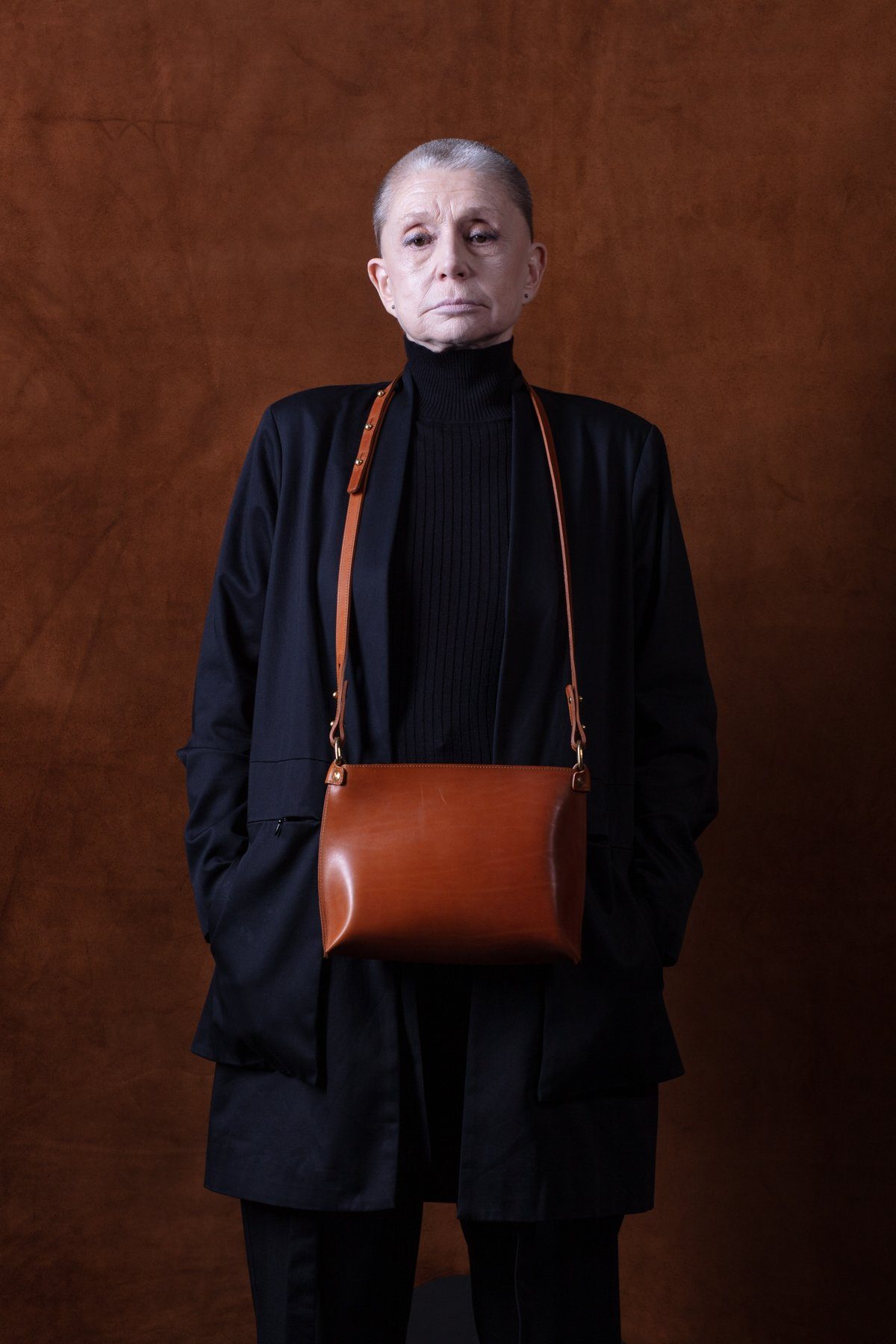 A woman in black wearing a tan leather crossbody bag